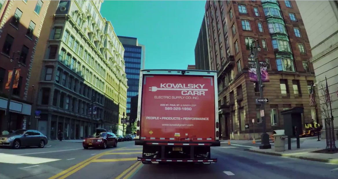 Kovalsky Carr delivery truck with logo on back, driving through downtown Rochester, NY